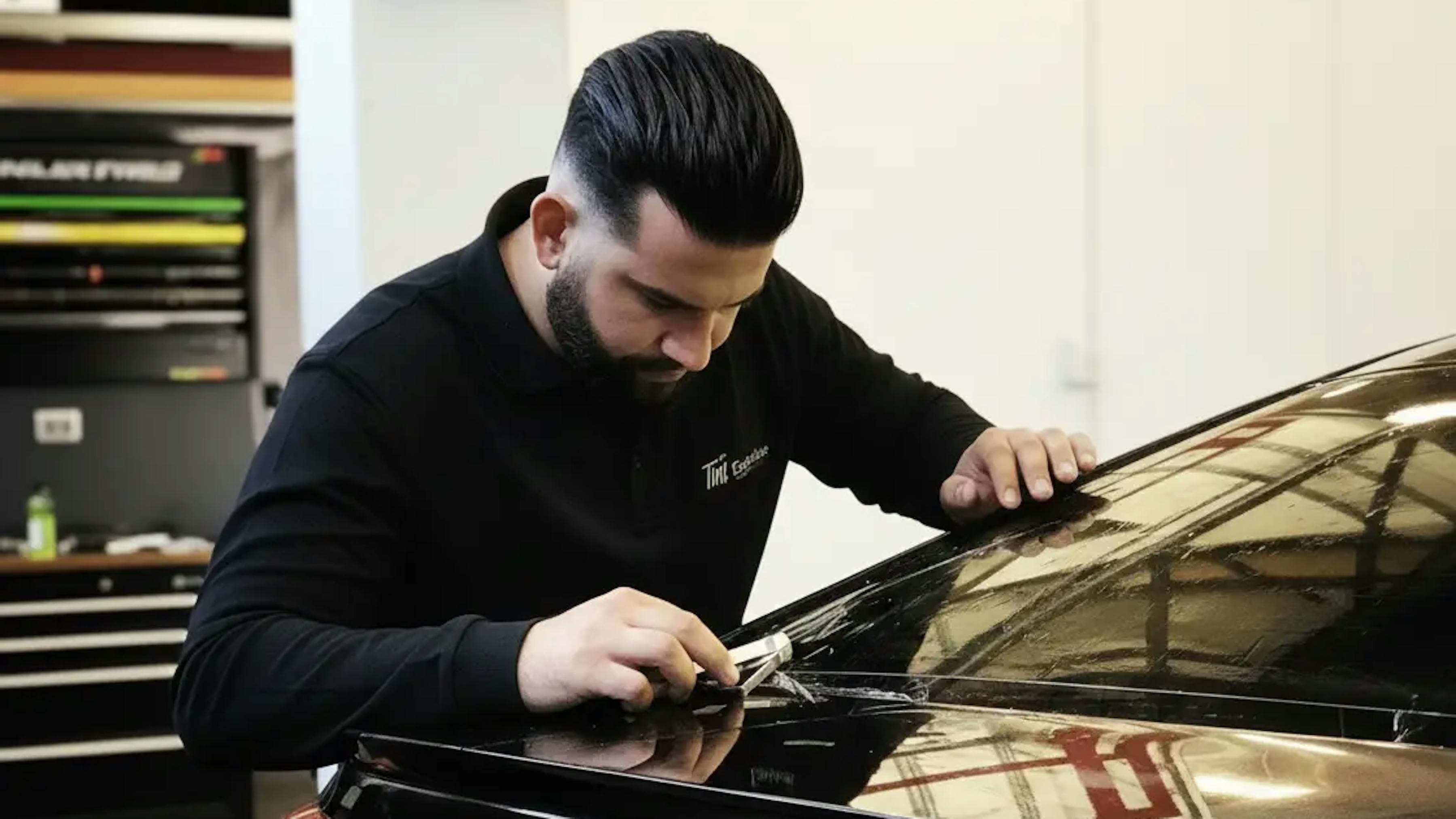 Tint Exclusive monteur brengt keramische folie aan op een auto